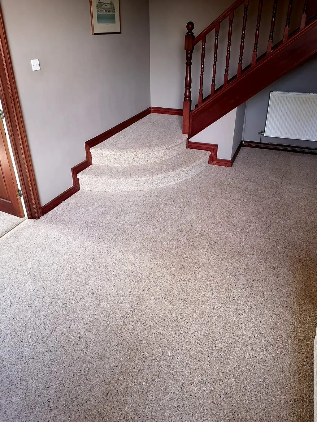 Neutral carpet fitted across a living room and up two curved bottom steps